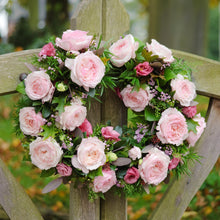 A wreath hanging of Keira roses and greenery - Frilly wedding-dress petals frame her cupped blooms in every shade of soft pink, from raspberry ripple to clotted cream.